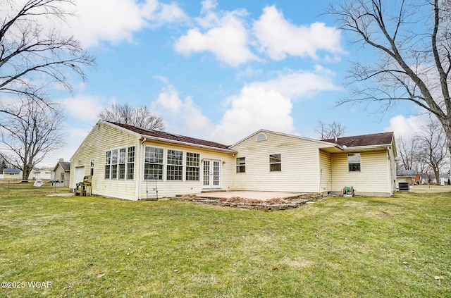 rear view of house featuring a garage, a patio area, and a lawn