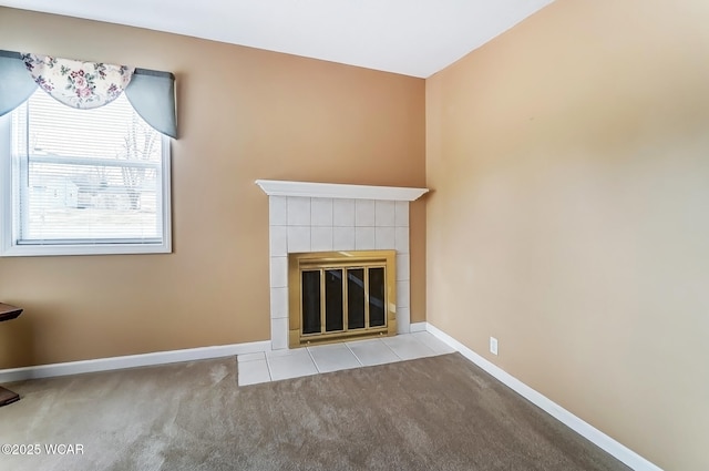 unfurnished living room with carpet floors, a tile fireplace, and baseboards