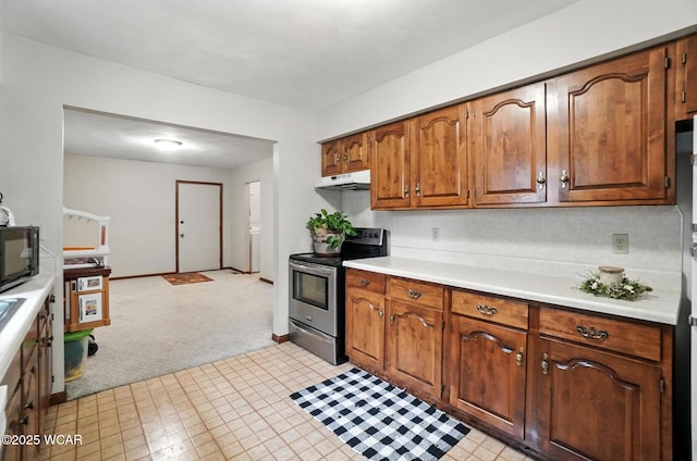 1619 Northbrook Dr, Lima, OH 45805 - kitchen with electric range, under cabinet range hood, light countertops, light carpet, and brown cabinetry
