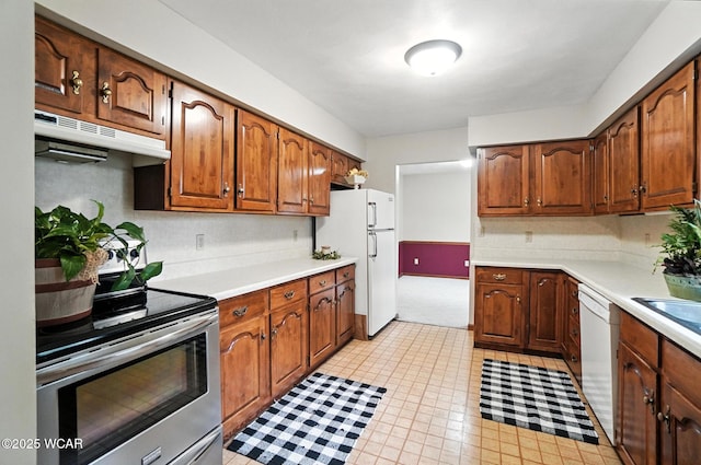 1619 Northbrook Dr, Lima, OH 45805 - kitchen with white appliances, under cabinet range hood, light countertops, light colored carpet, and brown cabinetry
