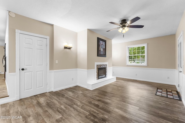 3139 Clifford Dr, Lima, OH 45805 - unfurnished living room featuring wainscoting, a fireplace with raised hearth, wood finished floors, and a ceiling fan