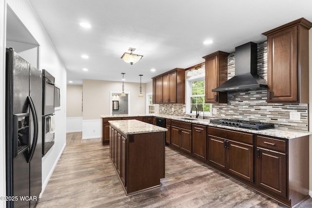 3139 Clifford Dr, Lima, OH 45805 - kitchen featuring wall chimney range hood, black refrigerator with ice dispenser, gas cooktop, a peninsula, and light wood-style flooring