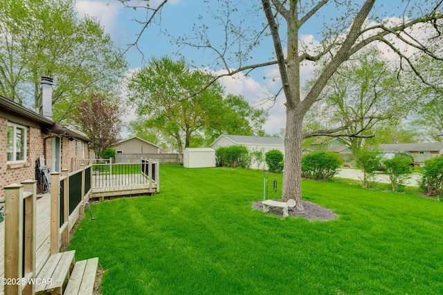 5295 E Rd, Lima, OH 45807 - view of yard featuring a deck, an outdoor structure, a fenced backyard, and a storage unit