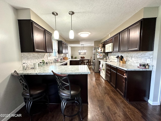 305 Fenway Dr, Lima, OH 45804 - kitchen featuring white appliances, a peninsula, dark brown cabinetry, dark wood-style flooring, and decorative backsplash
