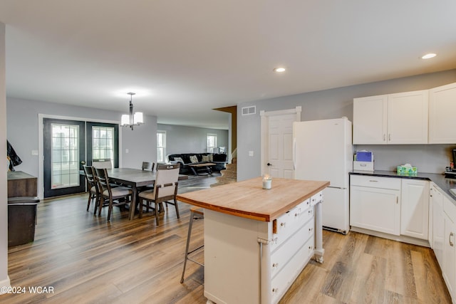 kitchen featuring a kitchen breakfast bar, a center island, white cabinets, and white fridge