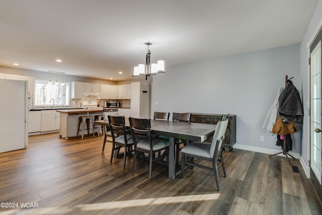 dining space with sink, dark hardwood / wood-style floors, and a chandelier