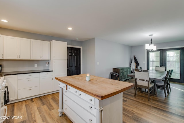 kitchen featuring white cabinetry, decorative light fixtures, a center island, and light hardwood / wood-style floors