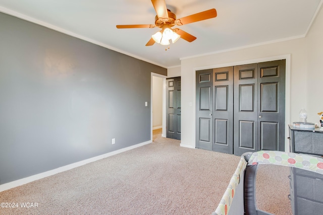 unfurnished bedroom with crown molding, carpet floors, a closet, and ceiling fan