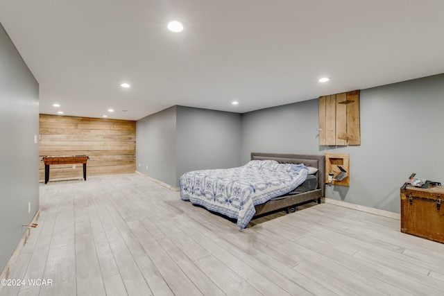 bedroom featuring wooden walls and light hardwood / wood-style floors