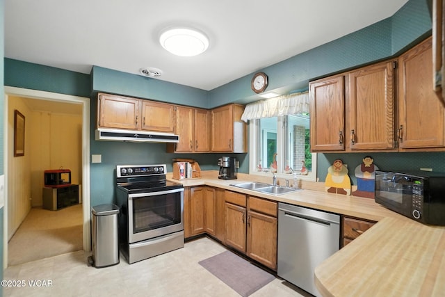 2619 Wendell Ave, Lima, OH 45805 - kitchen with appliances with stainless steel finishes, under cabinet range hood, light countertops, light flooring, and brown cabinetry