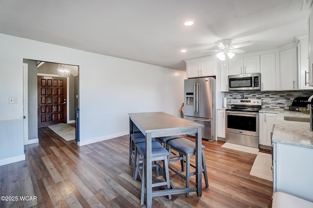 1280 Wonderlick Rd, Lima, OH 45805 - kitchen featuring stainless steel appliances, tasteful backsplash, wood finished floors, ceiling fan, and white cabinets