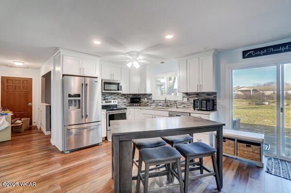 1280 Wonderlick Rd, Lima, OH 45805 - kitchen with appliances with stainless steel finishes, white cabinets, decorative backsplash, light wood-style flooring, and recessed lighting