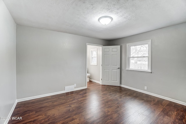 empty room featuring dark wood-type flooring and a textured ceiling