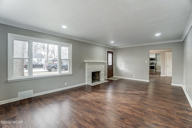 unfurnished living room with crown molding, a stone fireplace, and dark hardwood / wood-style floors