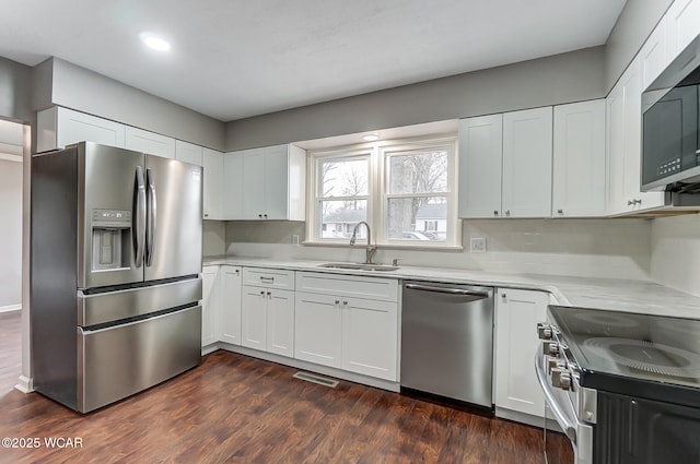 kitchen with appliances with stainless steel finishes, dark hardwood / wood-style floors, sink, and white cabinets