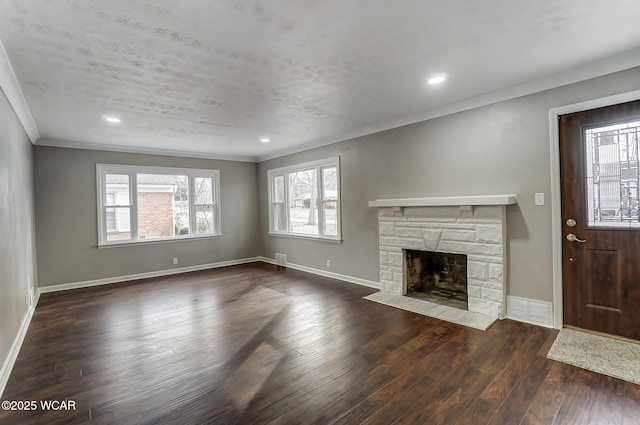 unfurnished living room with crown molding, a stone fireplace, and dark hardwood / wood-style flooring