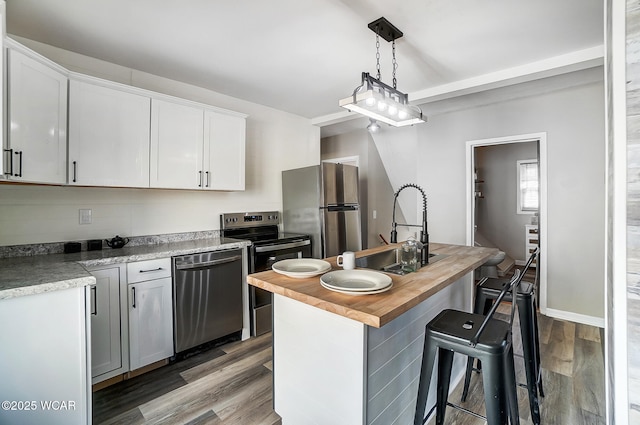 kitchen featuring a sink, wood counters, wood finished floors, appliances with stainless steel finishes, and white cabinets