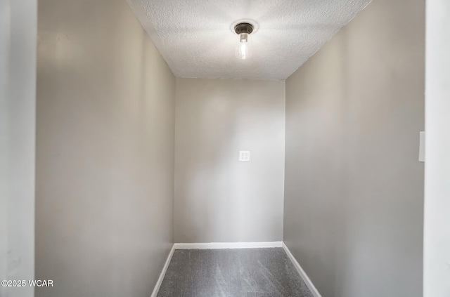 unfurnished room with carpet, baseboards, and a textured ceiling