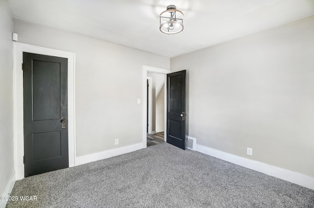 carpeted spare room featuring visible vents and baseboards