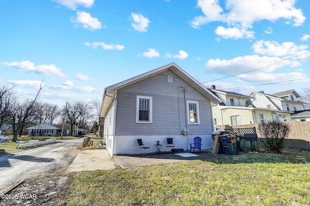 rear view of property featuring a patio, a yard, and fence