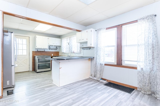 kitchen featuring white cabinets, appliances with stainless steel finishes, light wood-style flooring, and a peninsula