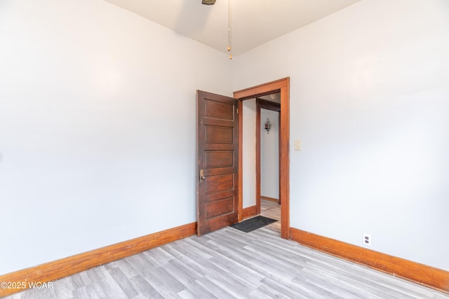 spare room featuring baseboards and light wood-style floors