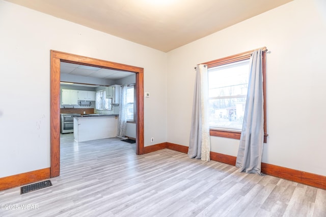 unfurnished room featuring visible vents, baseboards, and light wood finished floors