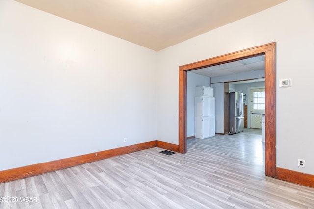 unfurnished room with a drop ceiling, visible vents, baseboards, and light wood-style flooring