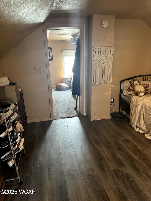 bedroom with vaulted ceiling, baseboards, dark wood-style flooring, and a textured ceiling