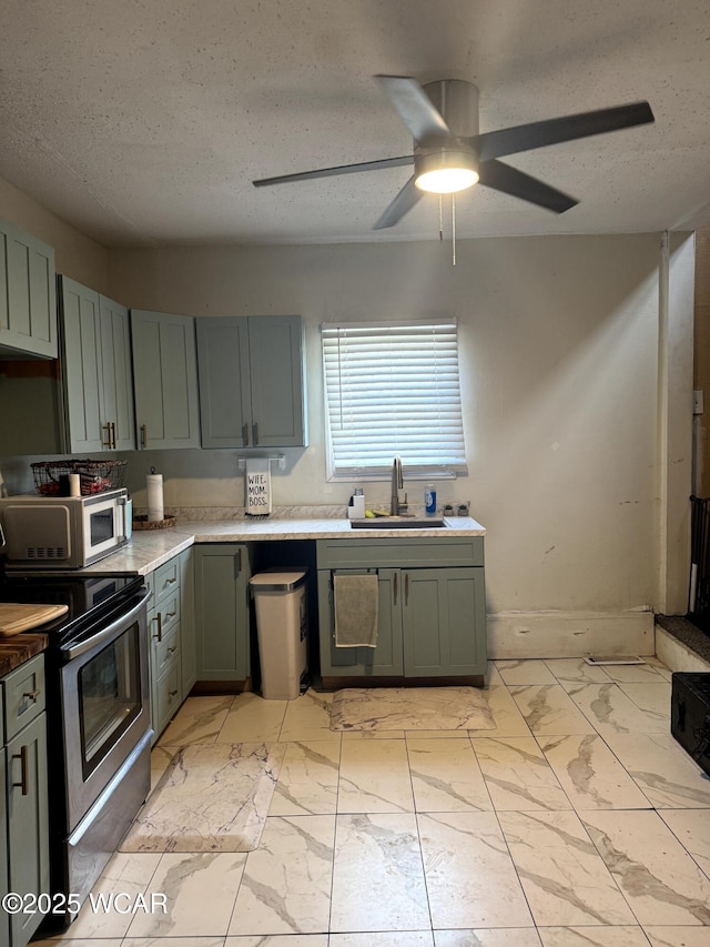 kitchen with marble finish floor, a ceiling fan, a sink, stainless steel electric stove, and a textured ceiling