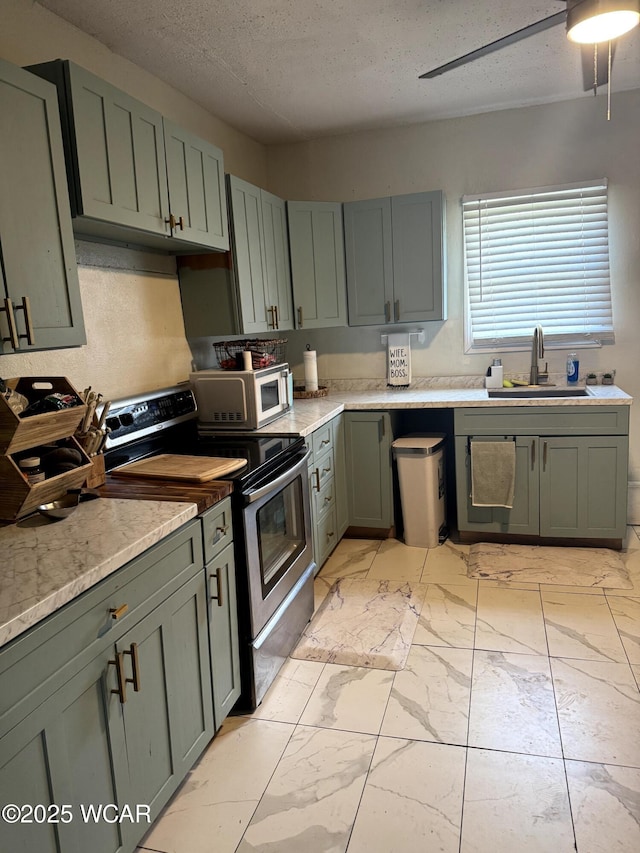 kitchen with ceiling fan, electric range, marble finish floor, a textured ceiling, and a sink