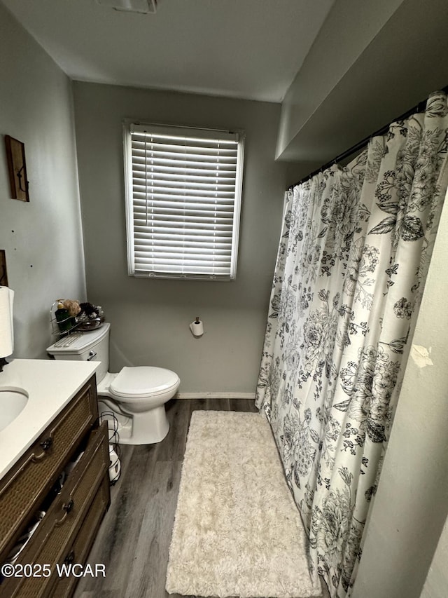 bathroom featuring toilet, curtained shower, wood finished floors, baseboards, and vanity