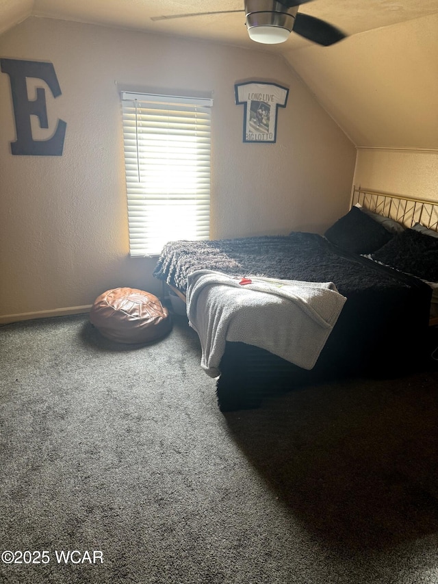 bedroom with a ceiling fan, vaulted ceiling, a textured wall, and carpet floors