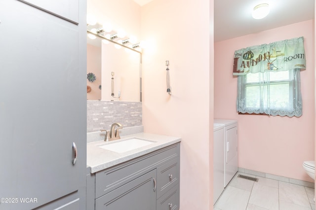 1380 Thomas Rd, New Paris, OH 45347 - bathroom featuring washer and dryer, tasteful backsplash, vanity, toilet, and tile patterned flooring