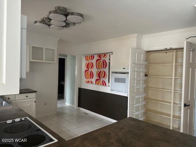 kitchen featuring white cabinetry, light tile patterned floors, ornamental molding, black electric stovetop, and oven