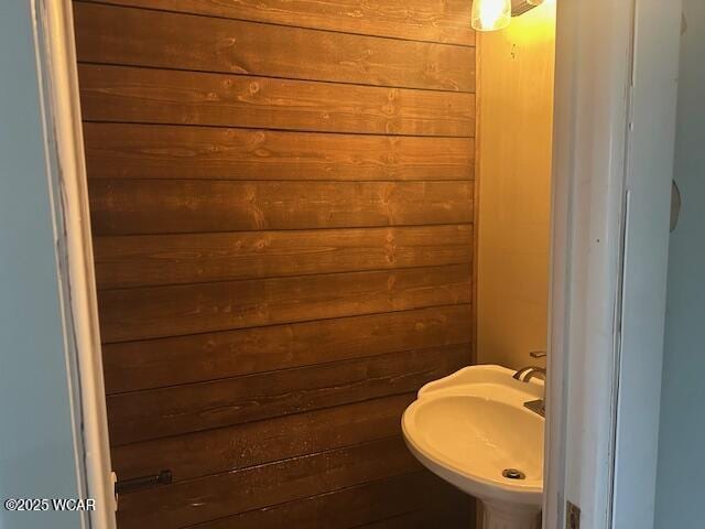 bathroom featuring wooden walls and sink