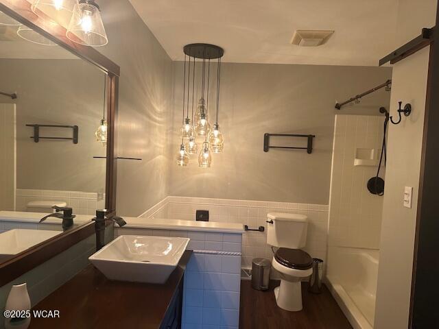 bathroom featuring hardwood / wood-style flooring, vanity, tile walls, and toilet