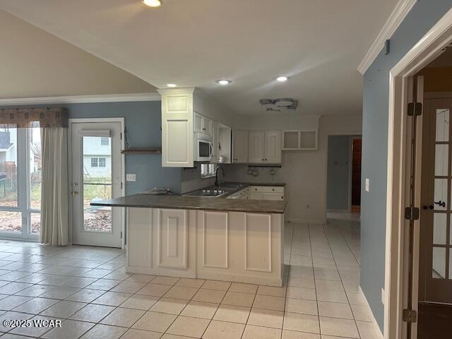 kitchen with light tile patterned floors, crown molding, kitchen peninsula, and white cabinets