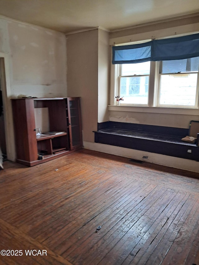 unfurnished living room featuring wood-type flooring and ornamental molding
