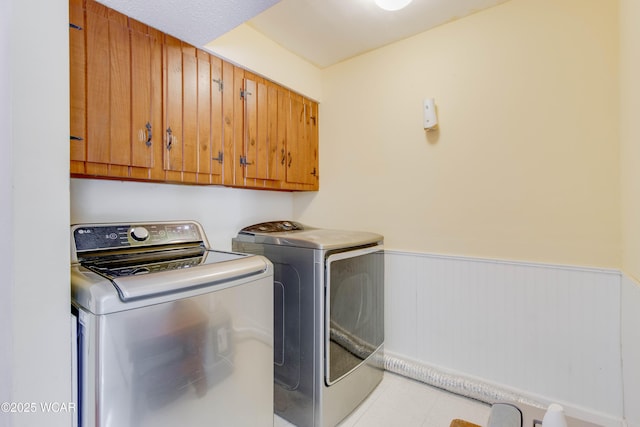 213 Johns Ave, Elida, OH 45807 - clothes washing area featuring washing machine and dryer, cabinet space, a wainscoted wall, and light tile patterned floors