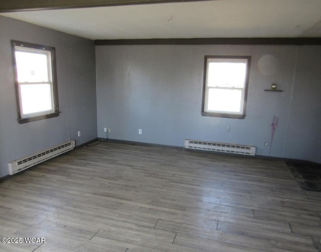 spare room featuring a baseboard heating unit and wood finished floors