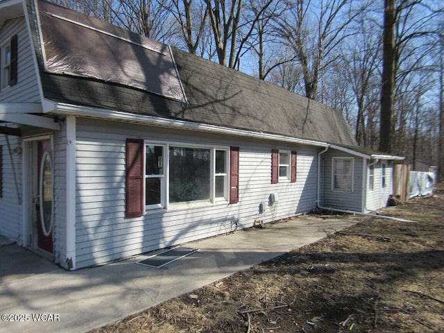 view of property exterior with a patio area and a shingled roof