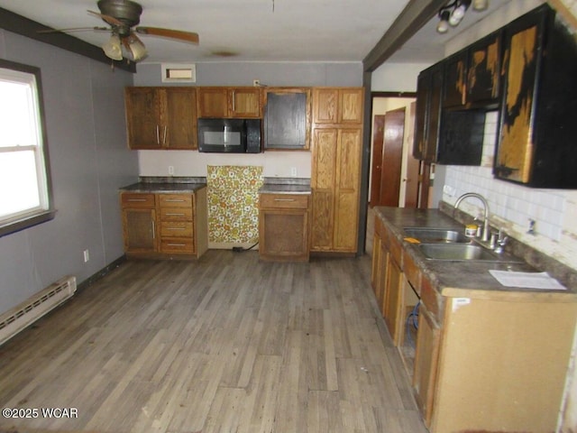 kitchen featuring light wood finished floors, brown cabinets, black microwave, and a sink