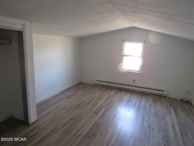 additional living space featuring a baseboard heating unit, vaulted ceiling, and wood finished floors