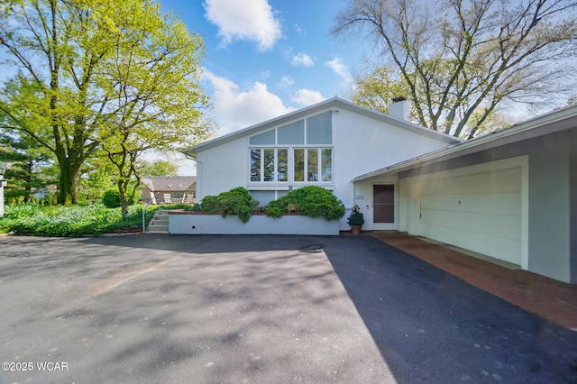 1275 Winterberry Dr, Lima, OH 45805 - view of front of house with asphalt driveway, a chimney, and stucco siding