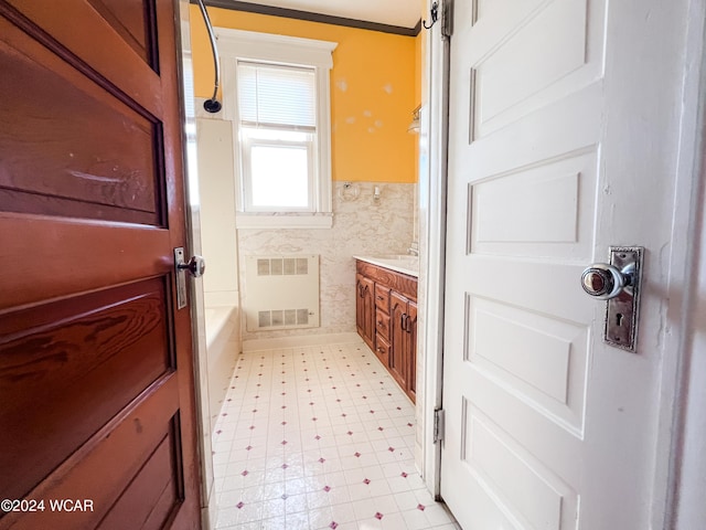 bathroom with vanity, a tub to relax in, and tile walls