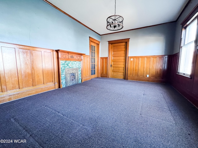 unfurnished living room with an inviting chandelier, crown molding, a fireplace, and carpet