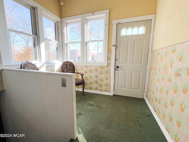 foyer entrance with dark colored carpet and a wealth of natural light