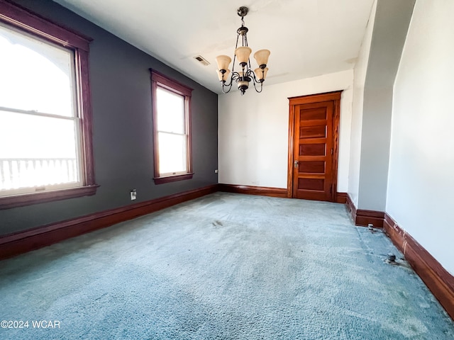 empty room with an inviting chandelier and carpet flooring