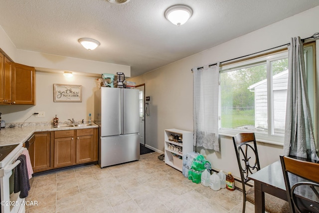 1153 Bahama Dr, Lima, OH 45801 - kitchen with freestanding refrigerator, a textured ceiling, brown cabinetry, white range with electric cooktop, and light countertops